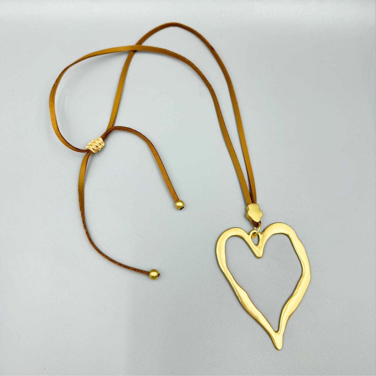 Open Heart Pendant Necklace - Silver with Black Cord, flat lay